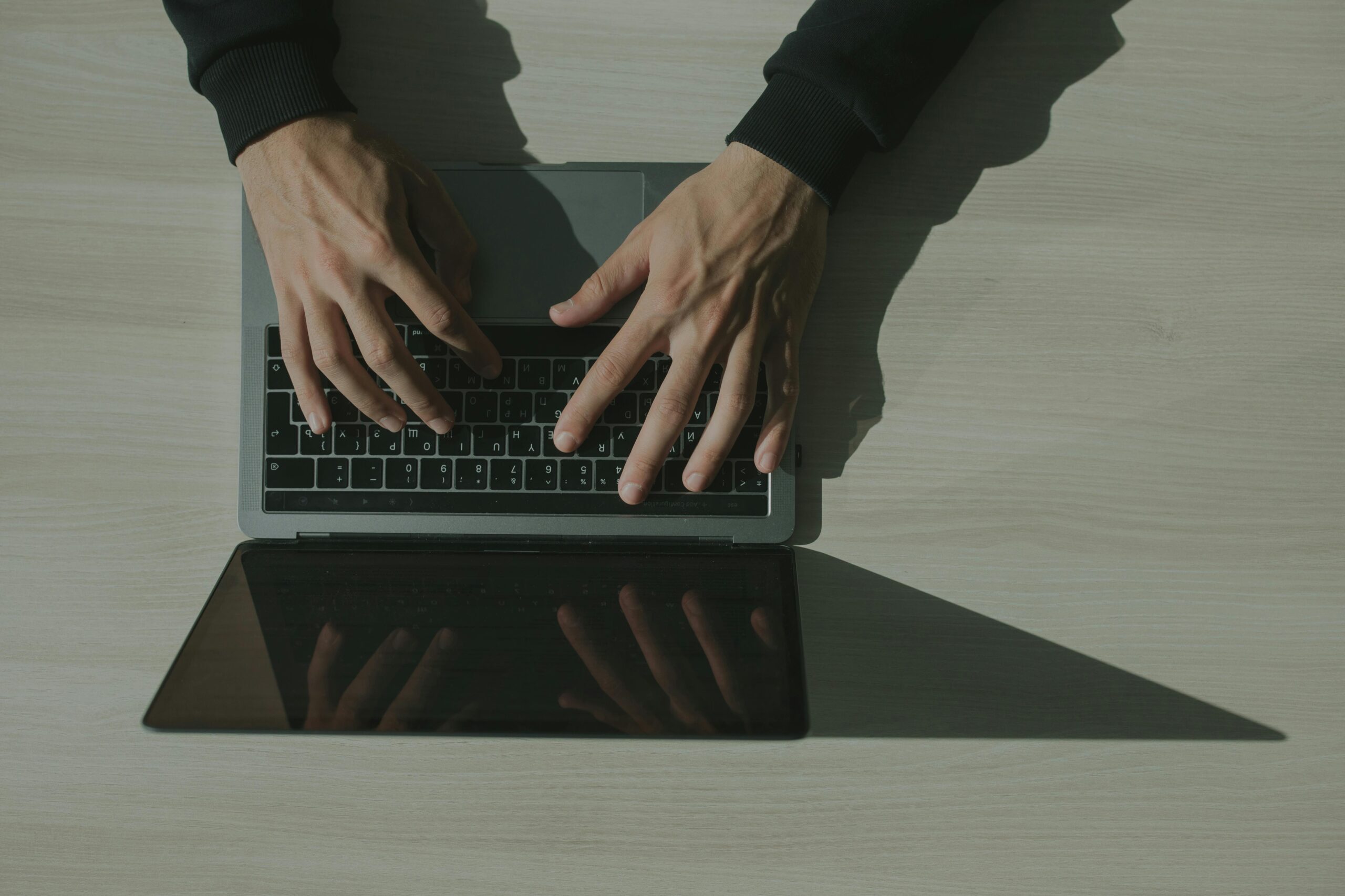 Overhead shot of hands typing on a laptop, showcasing technology and internet usage.